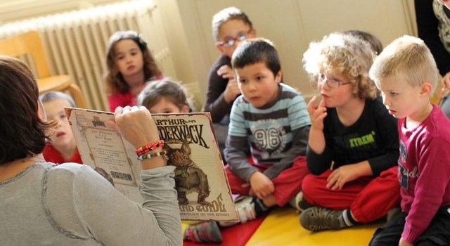 Woman reading a book to children