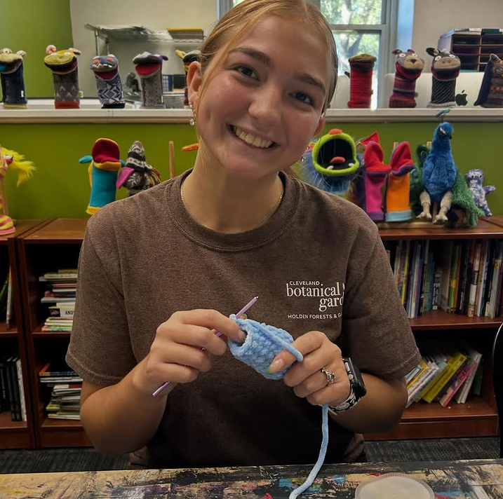 Crochet Club President Kayley Ramirez smiles with her crochet project.