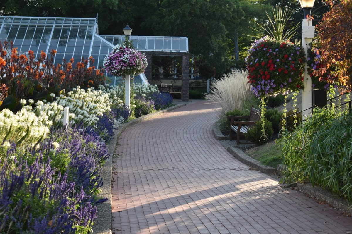 Brick path with flowers on either side and a greenhouse at Oglebay Park