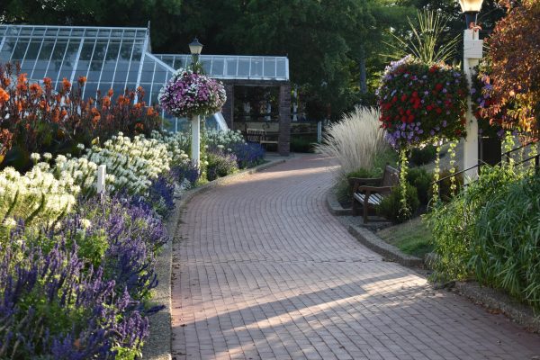Brick path with flowers on either side and a greenhouse at Oglebay Park